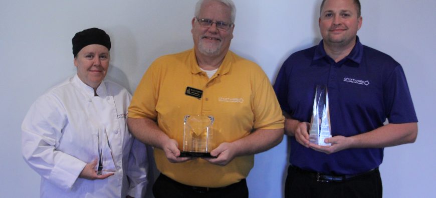 Two men and a woman holding plaques