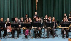 Group of band students sitting with their instruments in the auditorium