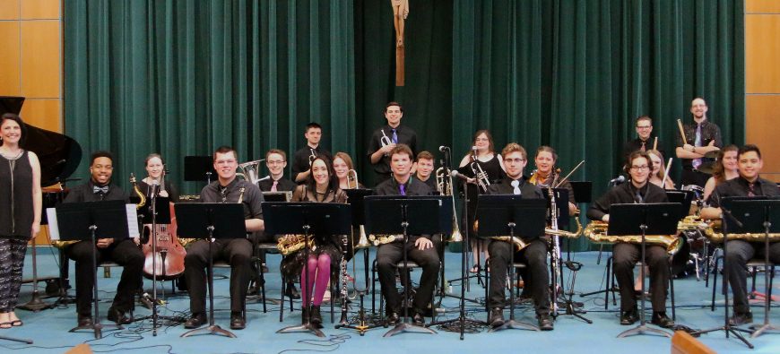 Group of band students sitting with their instruments in the auditorium