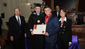 Two men holding an award with a woman