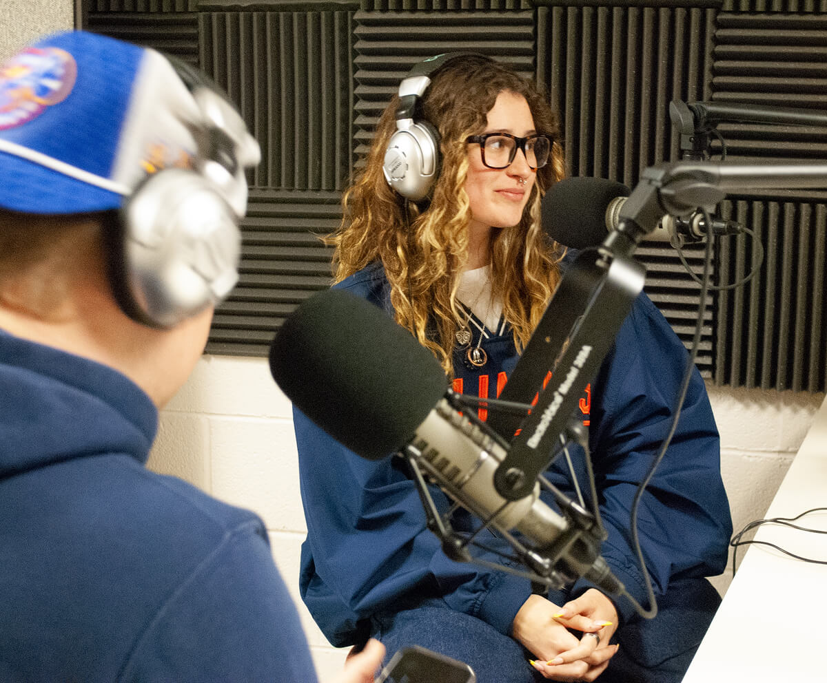 Two students hosting a podcast in studio wearing headsets