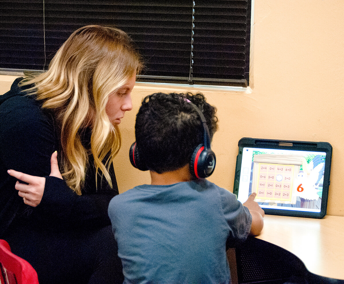 Student helping child who is playing a math game