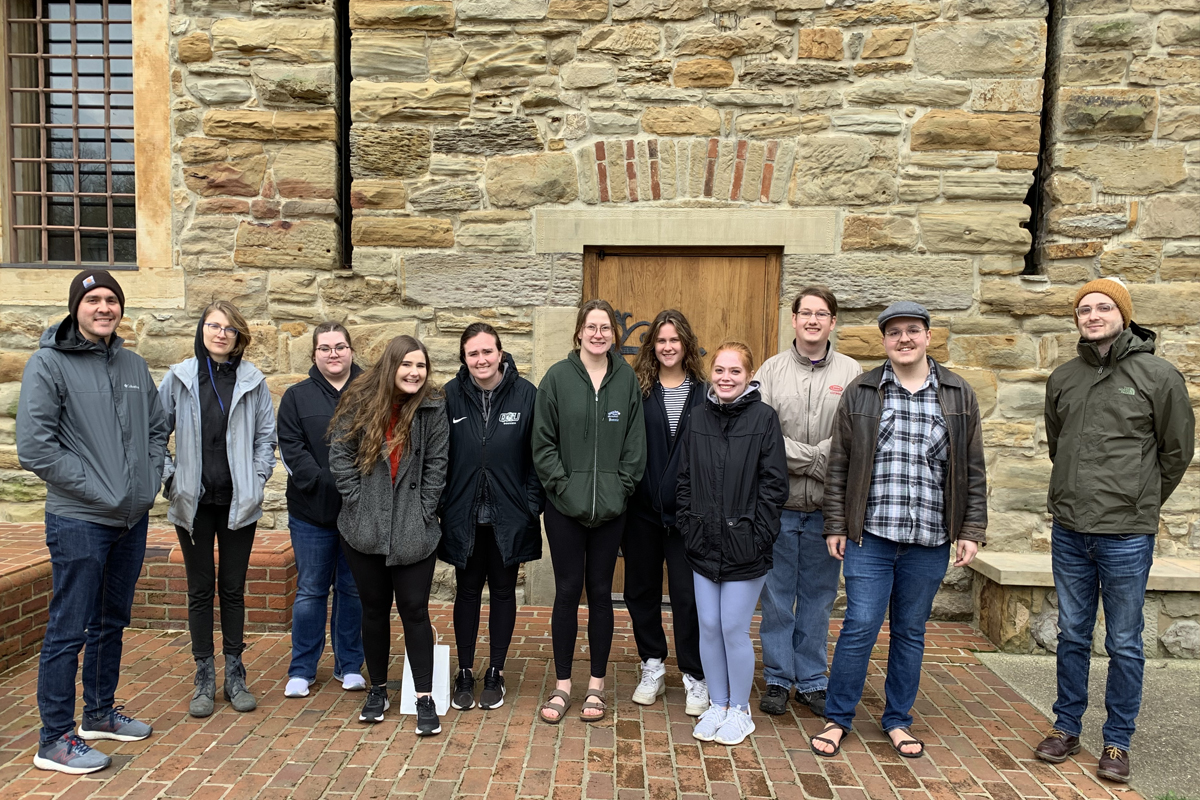Group of students standing infront of stone building