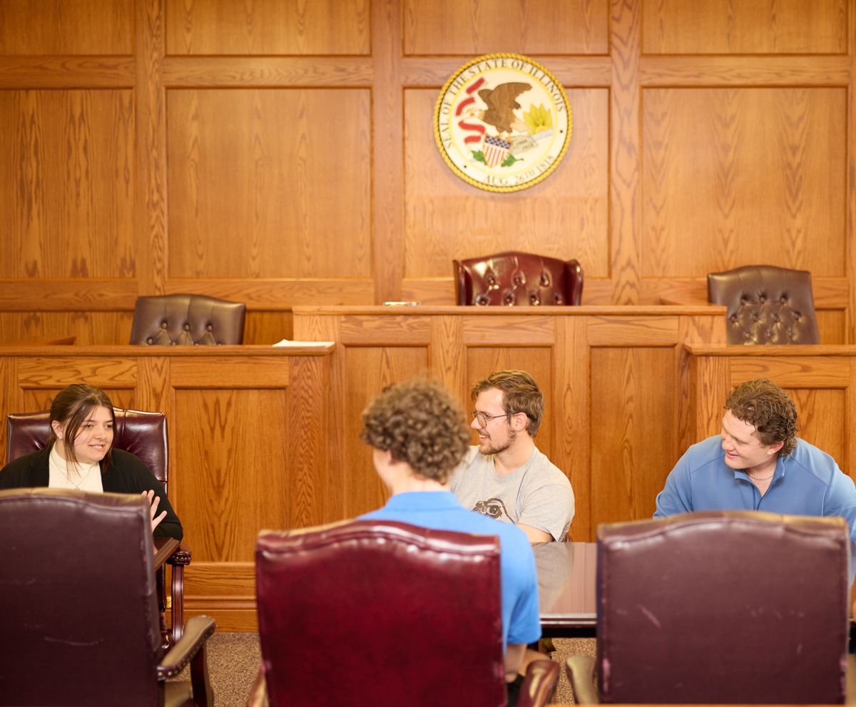 Four students in the QU court room having a discussion