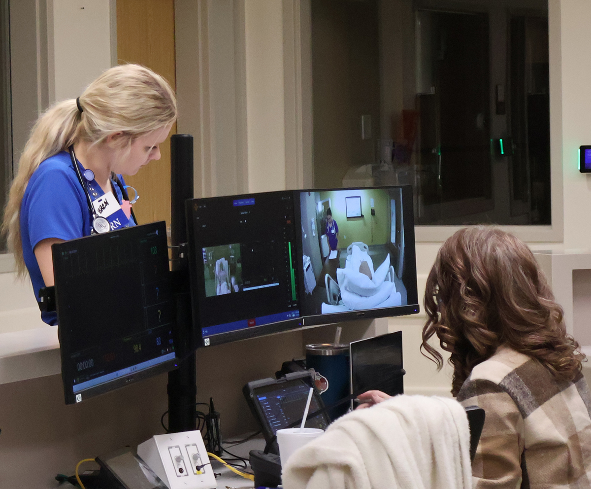 Nursing students at a simulation lab desk
