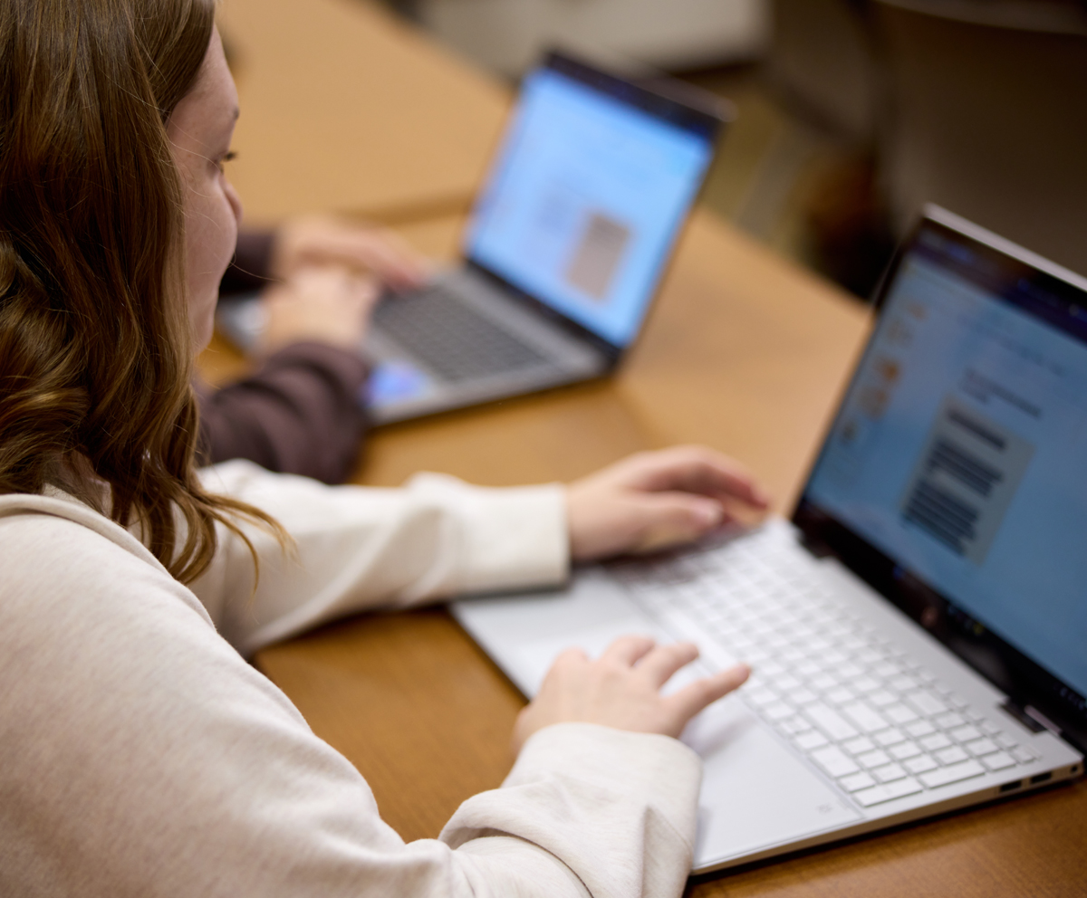 student looking down at open laptop