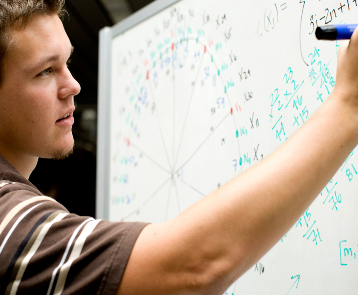 Student at whiteboard working on a math problem