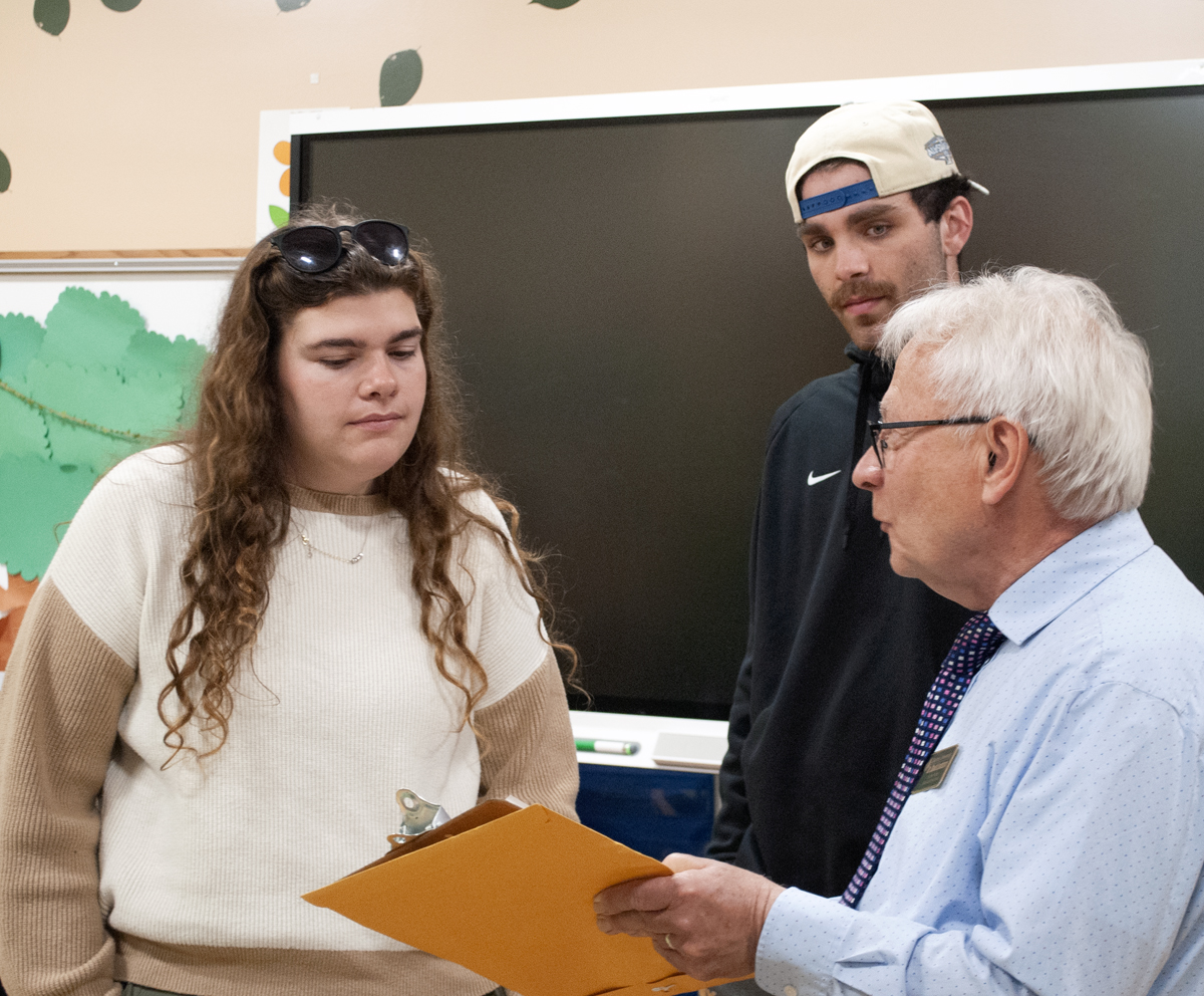Professor pointing at clipboard with two education students