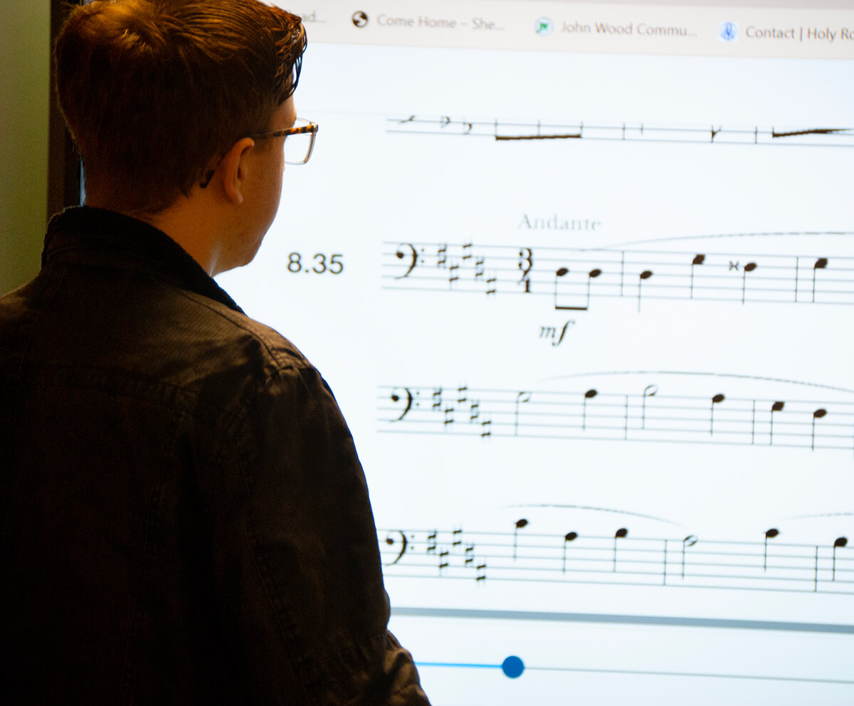 Close up of student facing a projection of sheet music