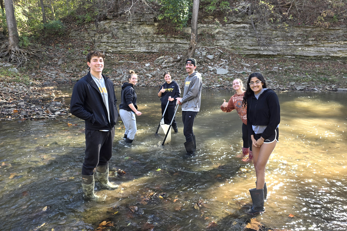 students standing in water who are part of a science group called stream team testing water