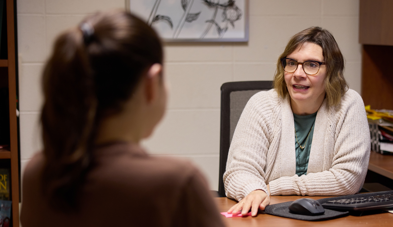 student and staff member sitting at desk