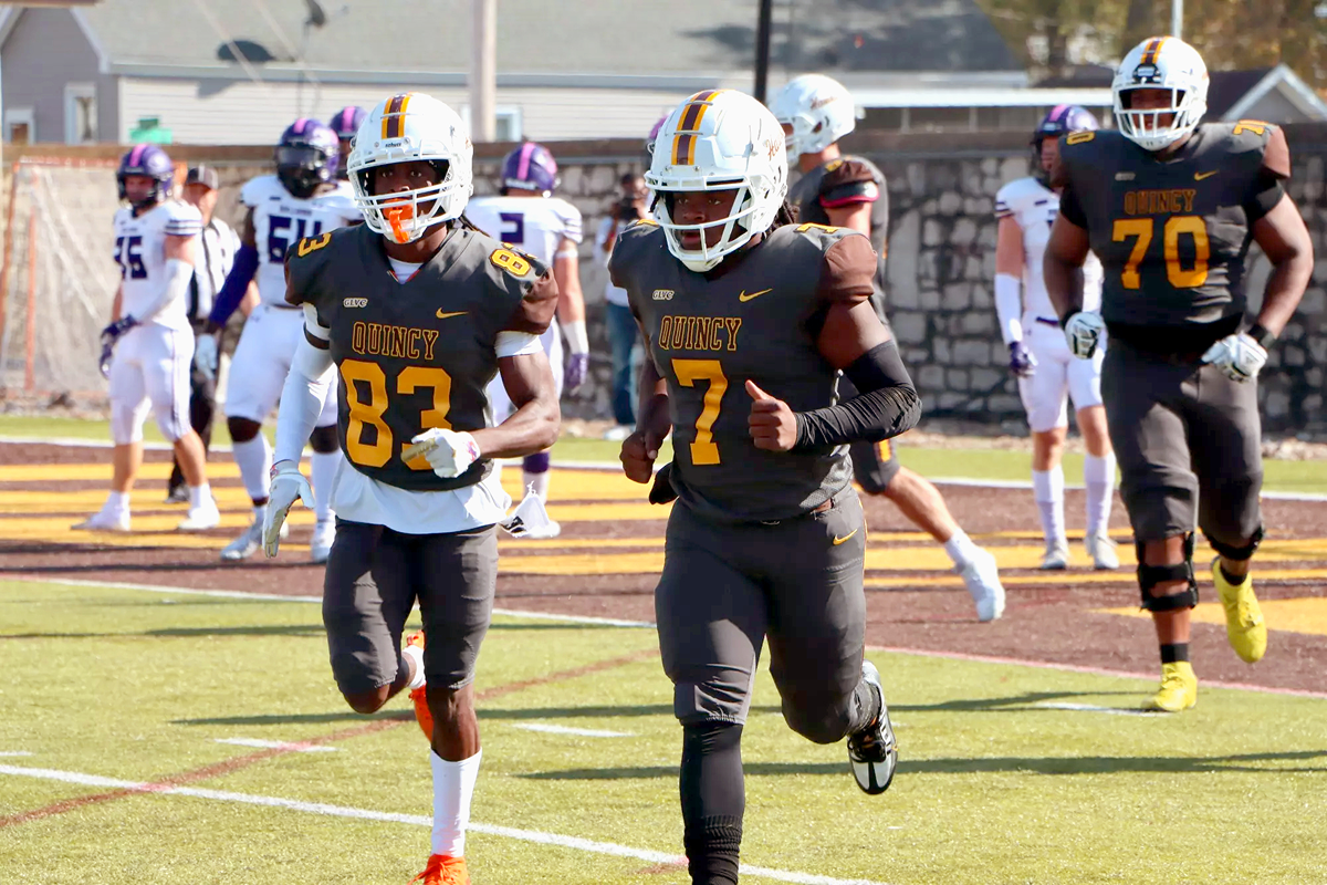 Quincy University's football team running onto the field.