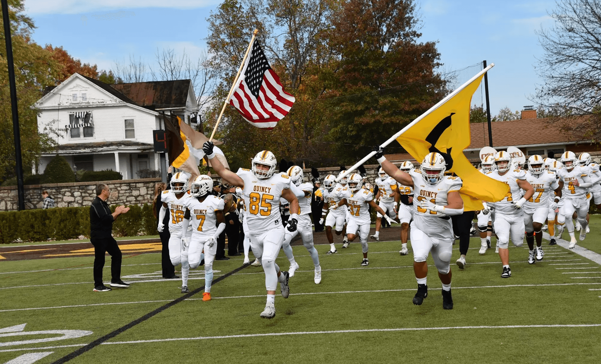 Quincy football team running onto the field at the start of a game.