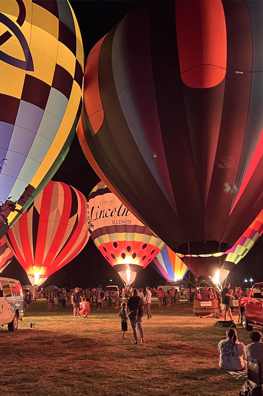 Hot air Balloons glowing on campus field.