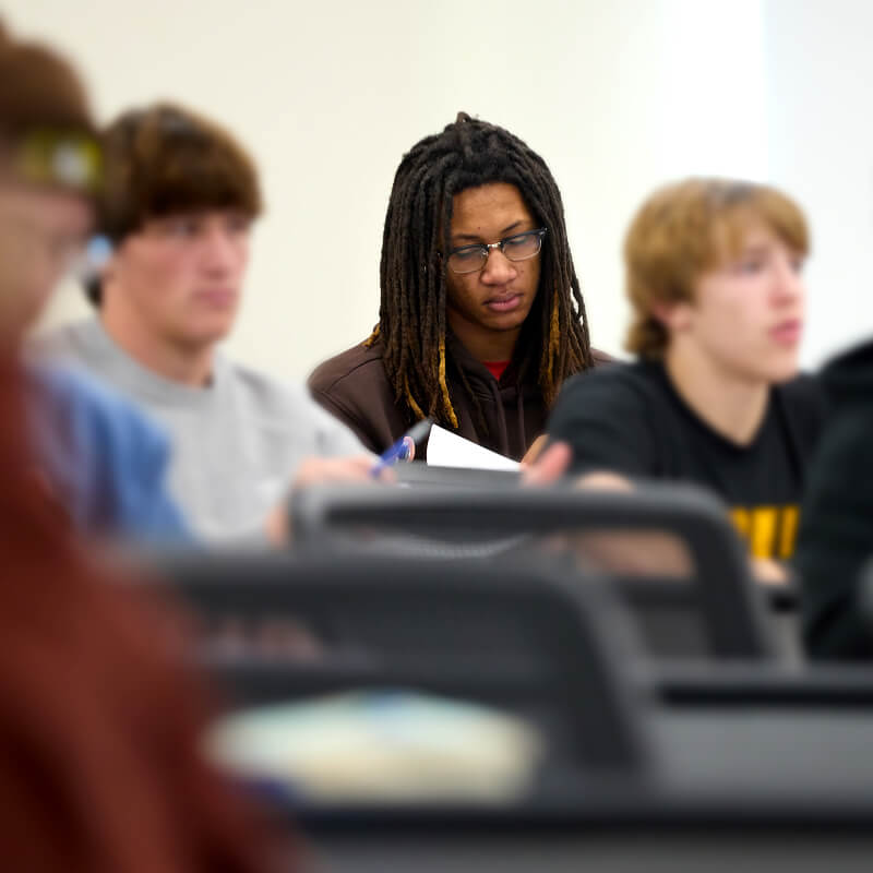 Close up of students in the classroom listening and taking notes