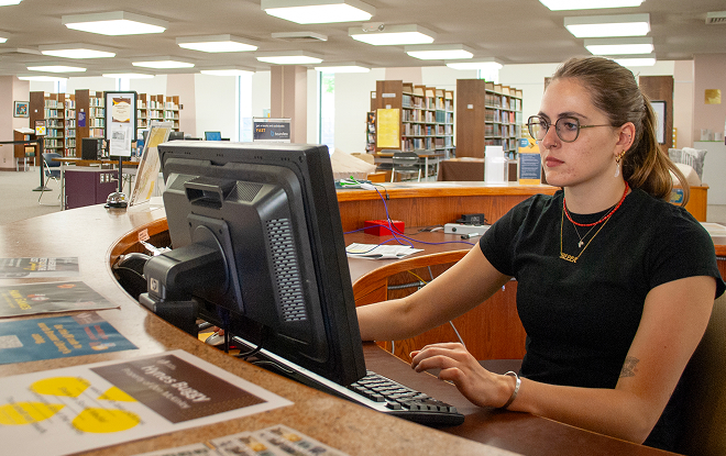 Librarian working at help desk inside the Brenner Library