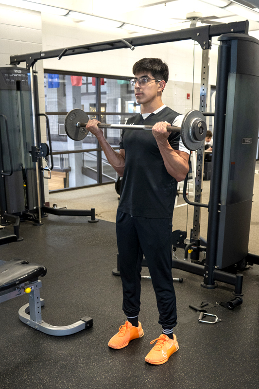 student lifting curl bar