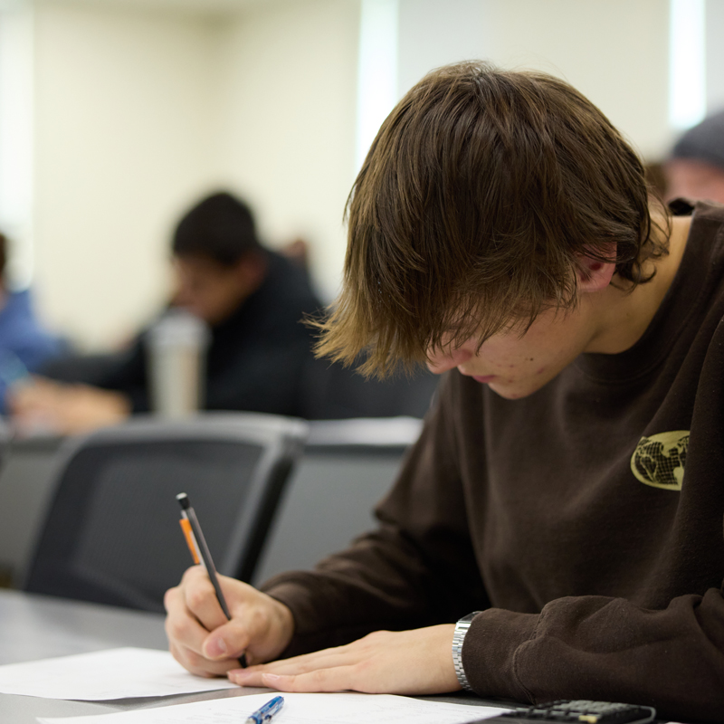 Male student in class writing in a notebook