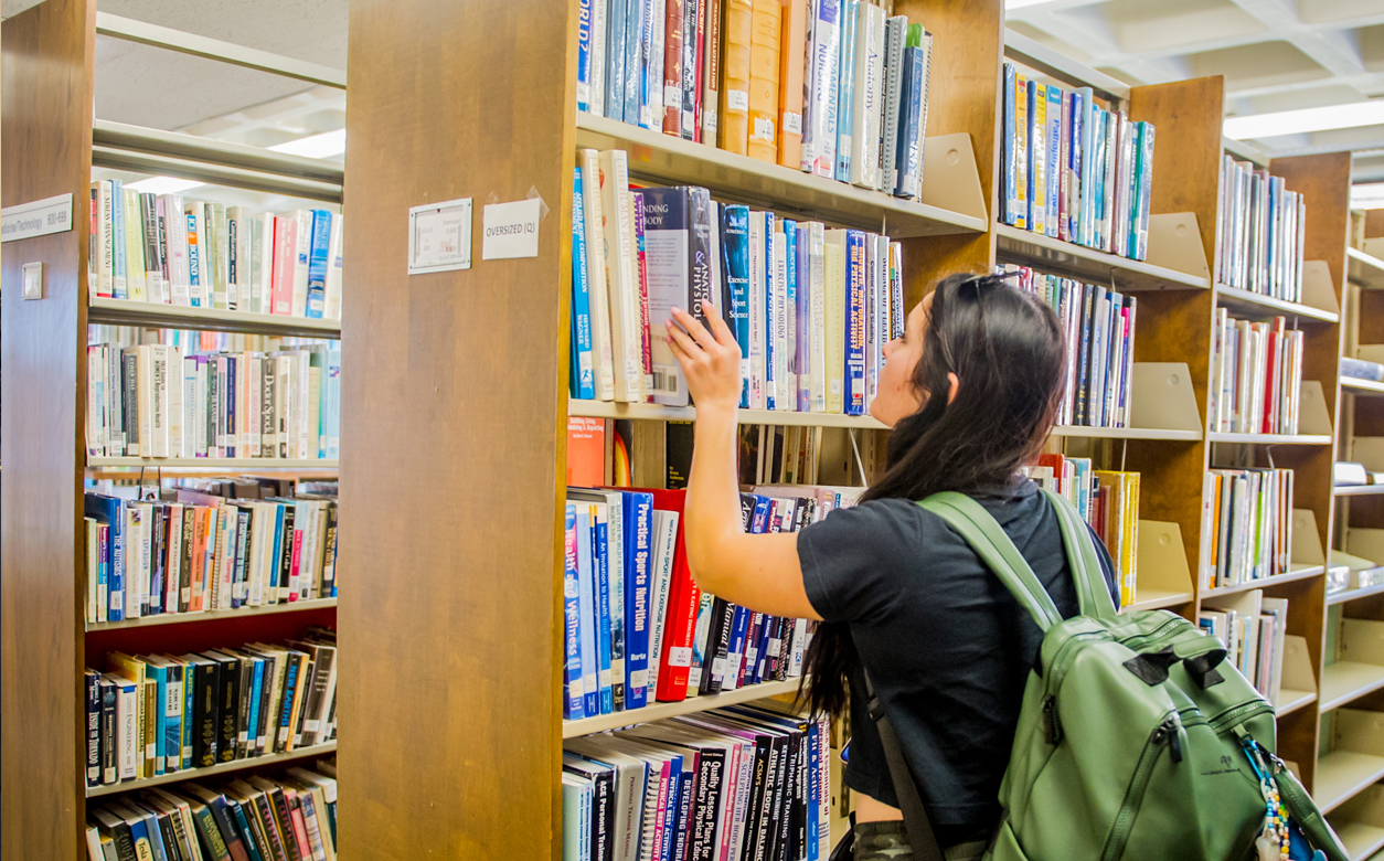 student in library picking out a book