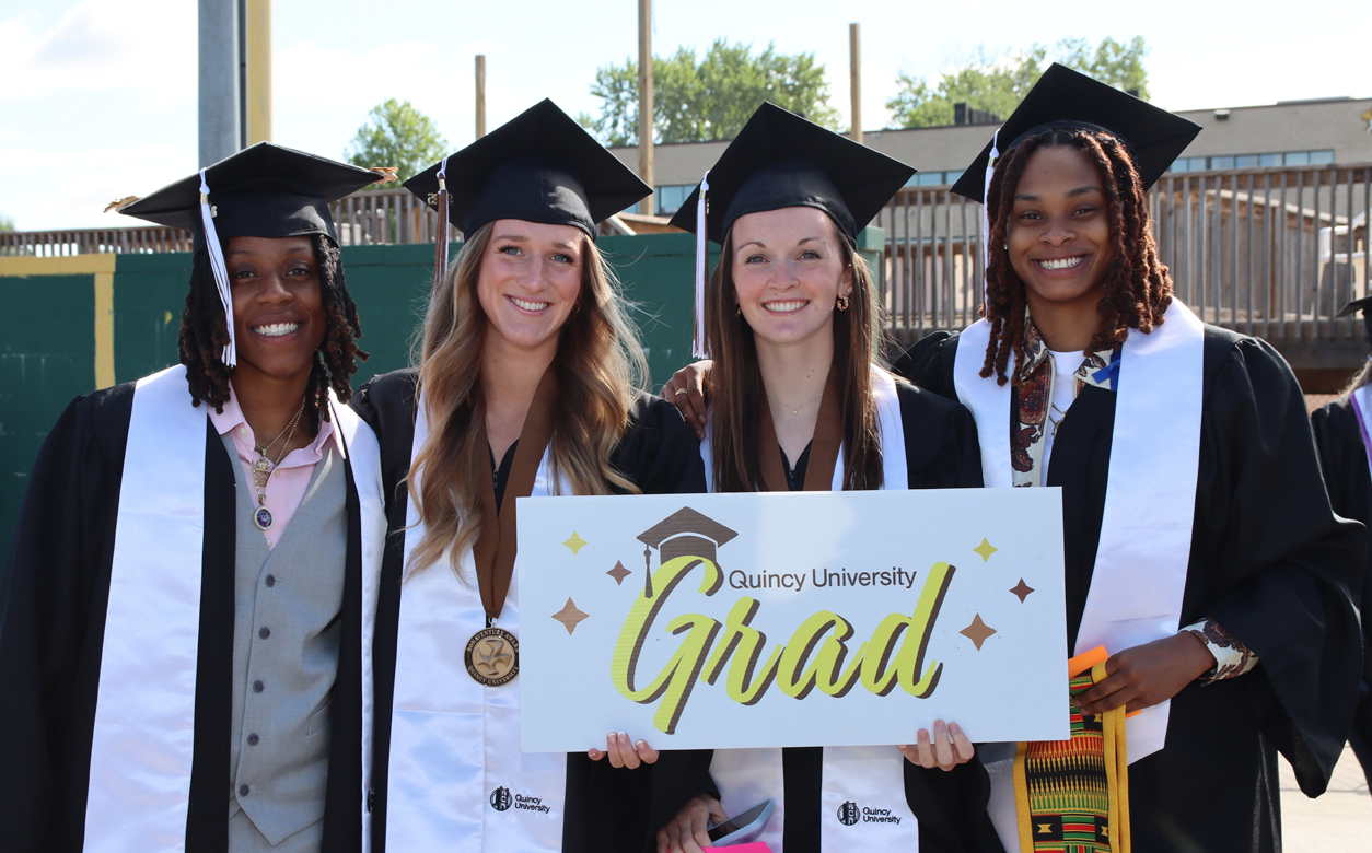 4 grad female students in cap and gowns