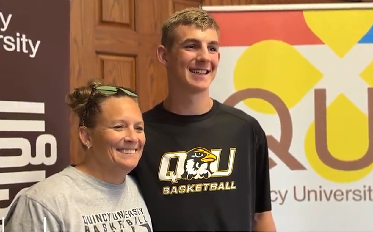 Mom and son infront of QU banner