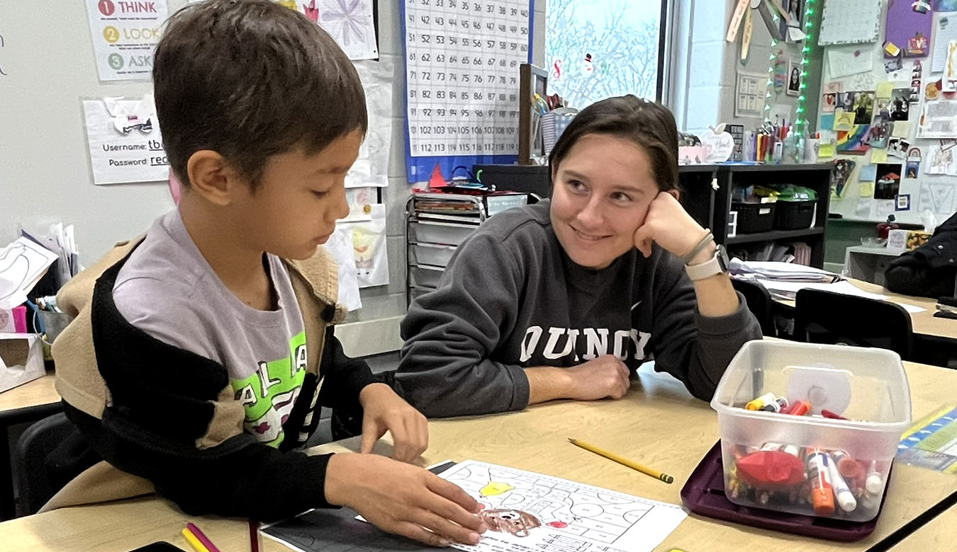 Female LaCrosse player watching an elementary boy color.