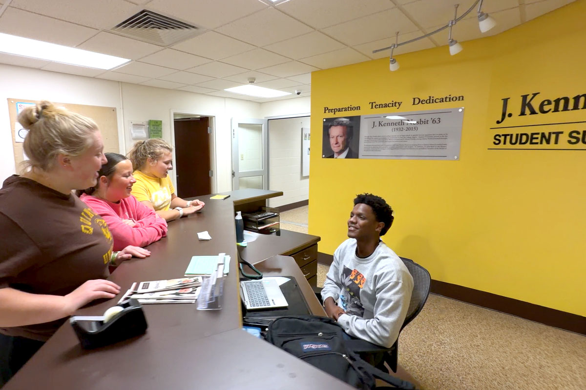 students standing near desk of the success center on campus