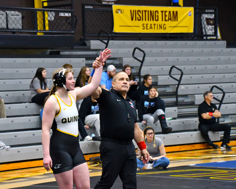 Women's wrestling student athlete holding arm up after just winning match
