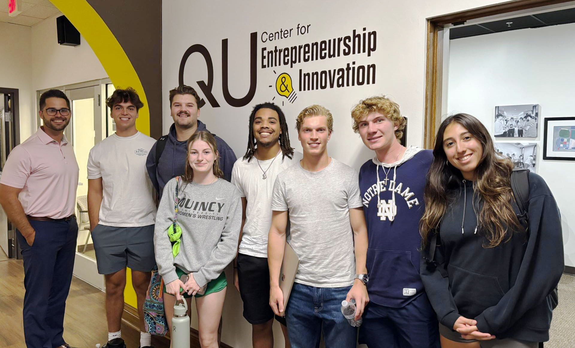 students in hallway standing in front of Entrepreneurship logo on wall