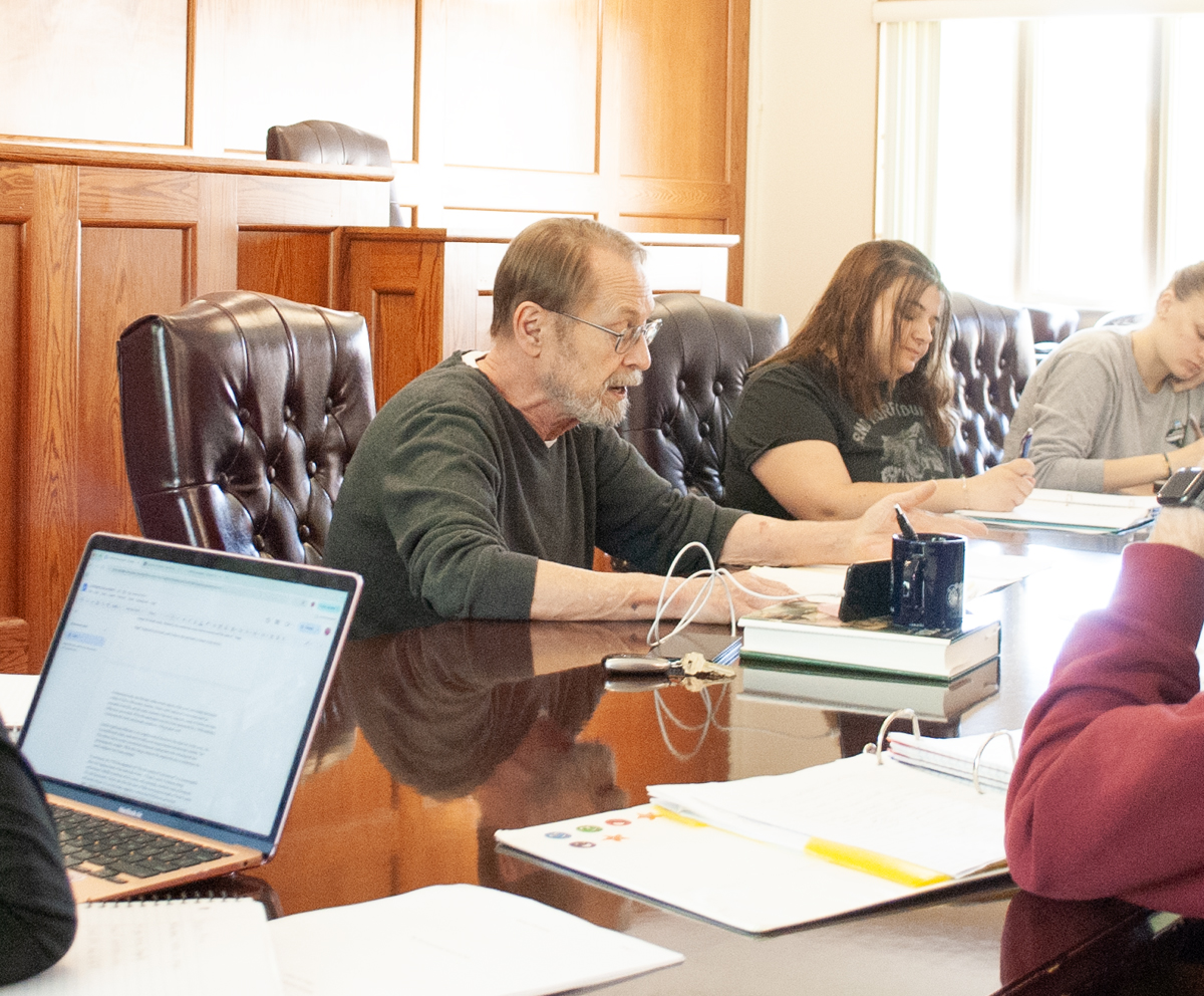 Students gathered around a table in the campus courtroom prelaw class