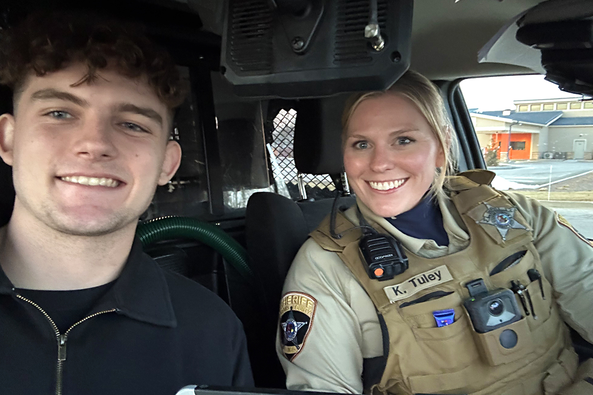 Male intern with a sheriff in a police car