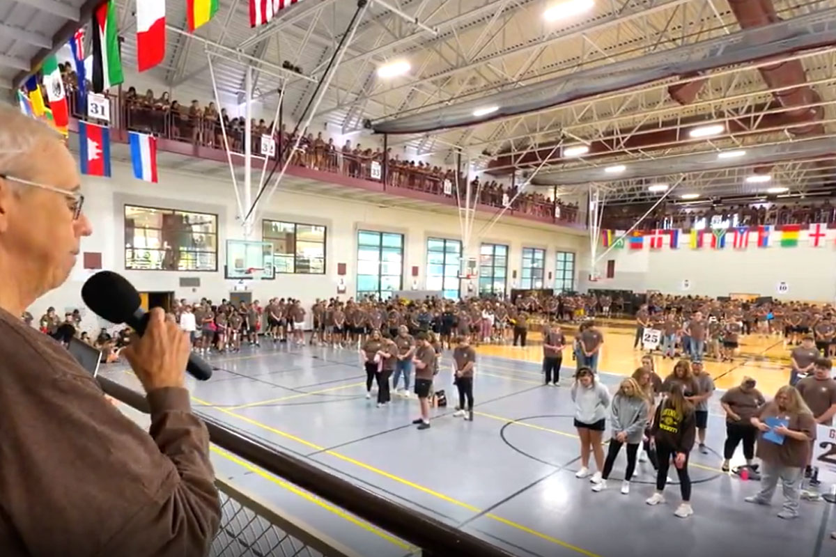 Fryer saying a prayer over students in a gym for day of service