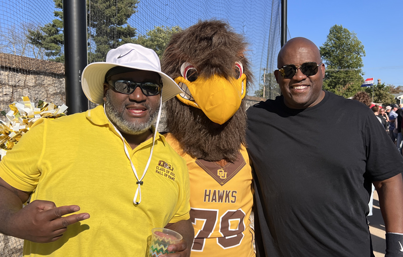 Two male Quincy alums with the hawk mascot