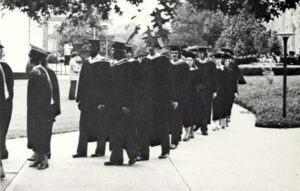 Black and white photo of a line of graduates