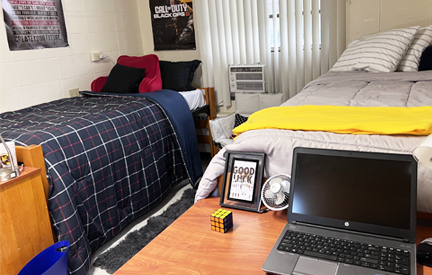 two twin beds in a dorm room next to a window with blinds.