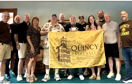 National Alumni Board group photo holding a QU flag